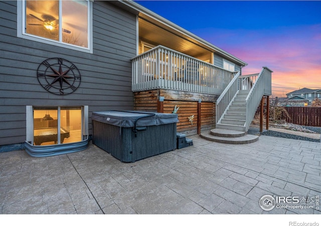 patio terrace at dusk featuring a hot tub