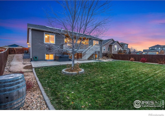 back house at dusk featuring a lawn and a patio area