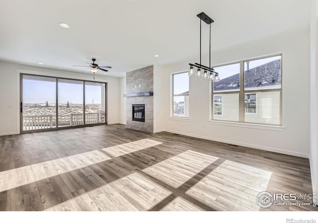 unfurnished living room with baseboards, wood finished floors, and a tile fireplace