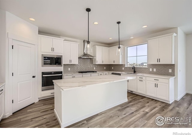 kitchen with black stovetop, stainless steel microwave, a kitchen island, wall chimney range hood, and oven