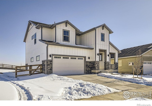 view of front facade featuring an attached garage, board and batten siding, fence, stone siding, and driveway