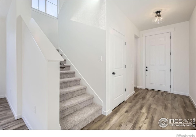 entryway featuring stairs, baseboards, and wood finished floors