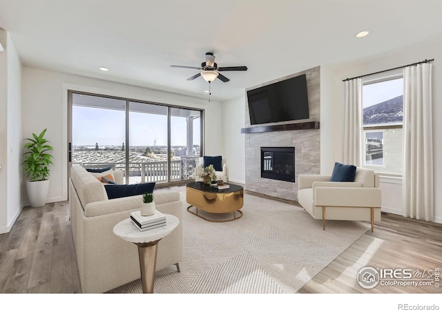 living room featuring a tiled fireplace, wood finished floors, a ceiling fan, and recessed lighting