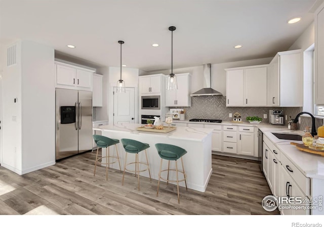 kitchen featuring tasteful backsplash, a kitchen island, a sink, wall chimney range hood, and black appliances