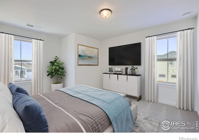 bedroom with carpet floors, baseboards, multiple windows, and visible vents