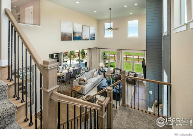 living room with ceiling fan, a towering ceiling, and a healthy amount of sunlight