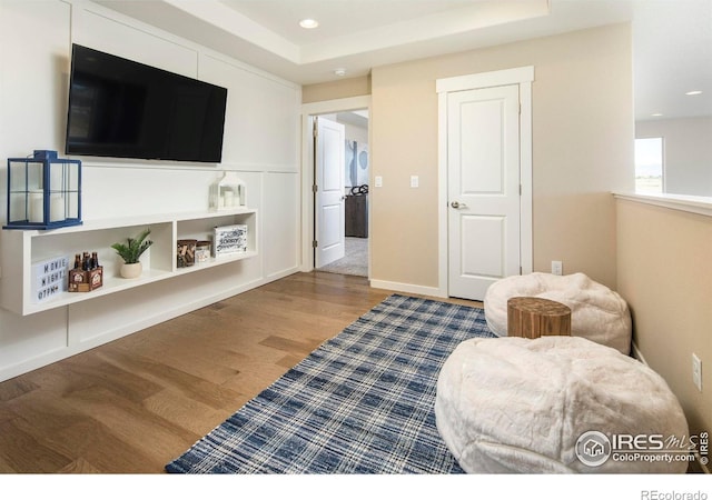 sitting room with wood-type flooring and a tray ceiling