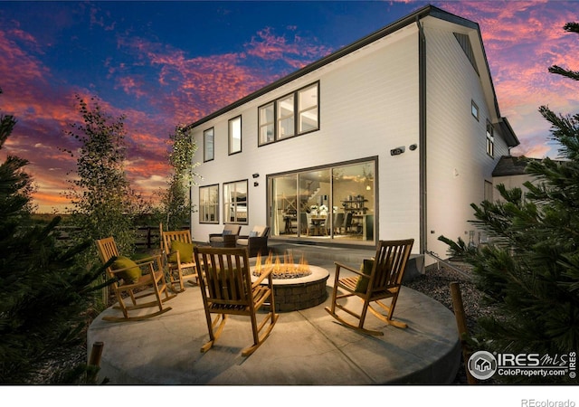 back house at dusk with an outdoor fire pit and a patio area