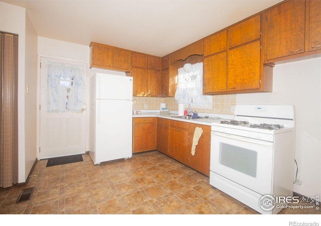 kitchen with sink, white appliances, and backsplash