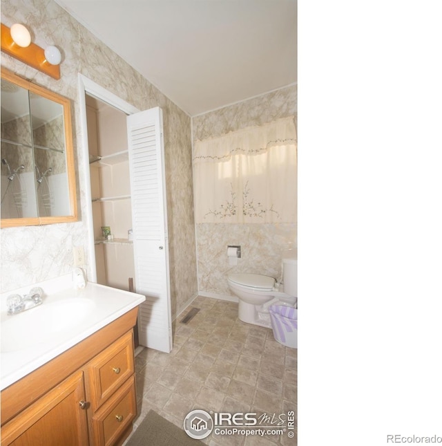 bathroom featuring vanity, toilet, and tile walls