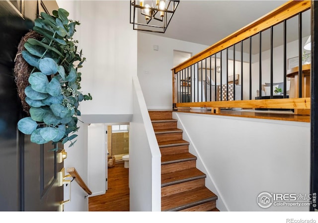 staircase featuring hardwood / wood-style flooring, plenty of natural light, and an inviting chandelier