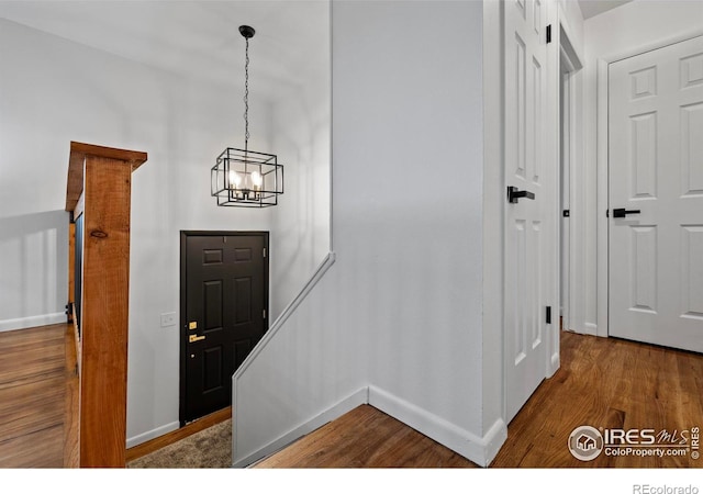 foyer with wood-type flooring and a notable chandelier