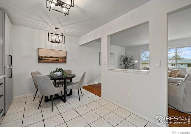 dining space with light hardwood / wood-style floors and an inviting chandelier