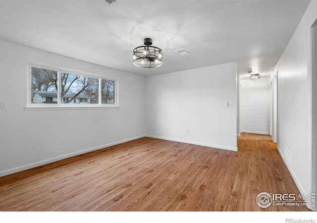 empty room with a chandelier and light hardwood / wood-style floors