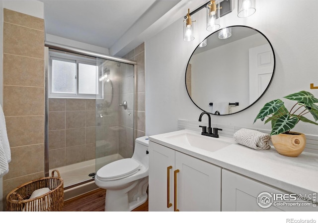 bathroom featuring vanity, wood-type flooring, a shower with shower door, and toilet