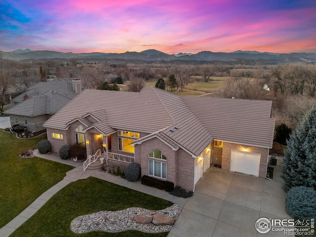 ranch-style home featuring a mountain view, a garage, and a lawn