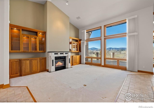 carpeted living room featuring a mountain view, a healthy amount of sunlight, and high vaulted ceiling