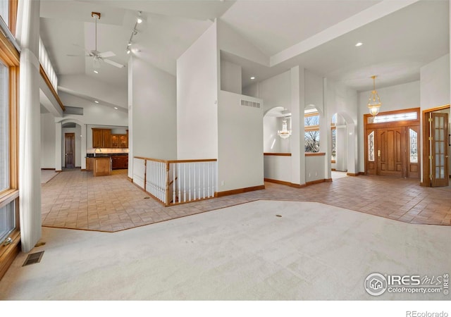 entryway featuring light carpet and high vaulted ceiling