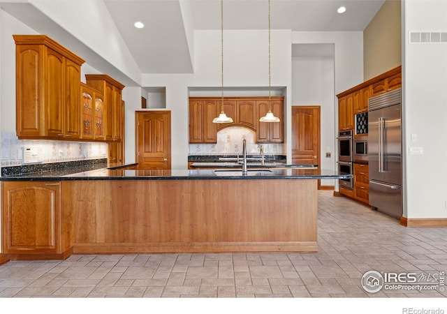 kitchen with decorative backsplash, sink, hanging light fixtures, and appliances with stainless steel finishes