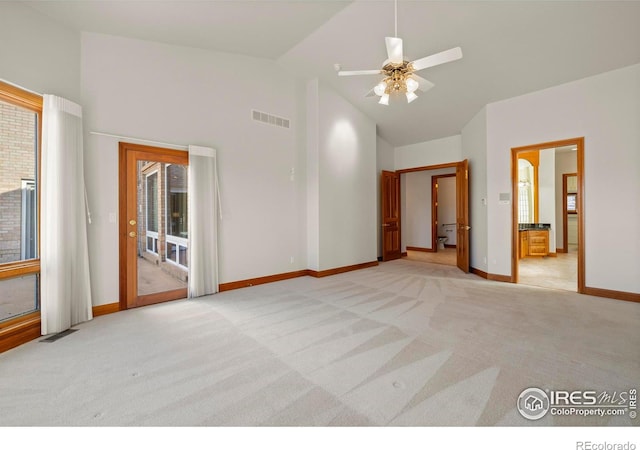 carpeted spare room with ceiling fan and high vaulted ceiling