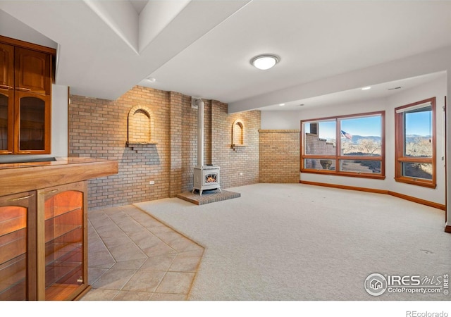 carpeted living room with a wood stove and brick wall