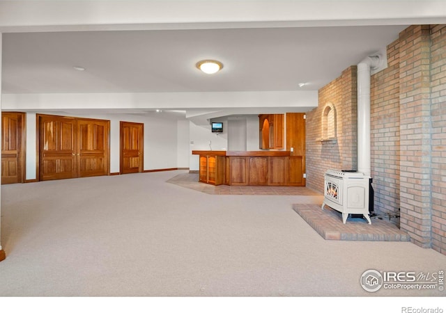 interior space featuring a wood stove, light colored carpet, and brick wall