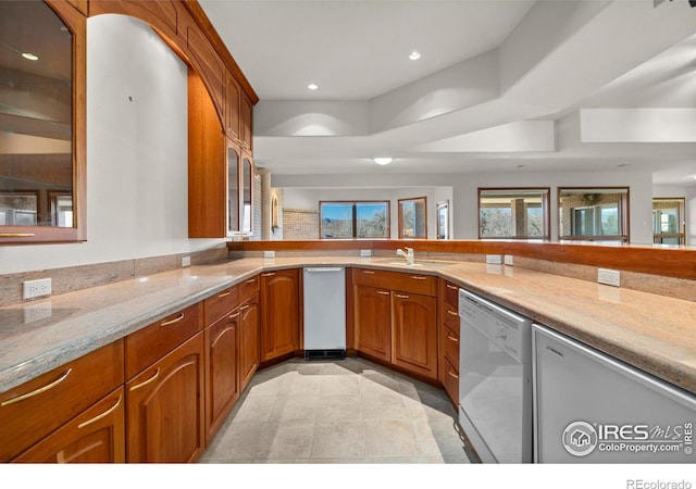 kitchen featuring dishwasher, light stone countertops, sink, and light tile patterned floors