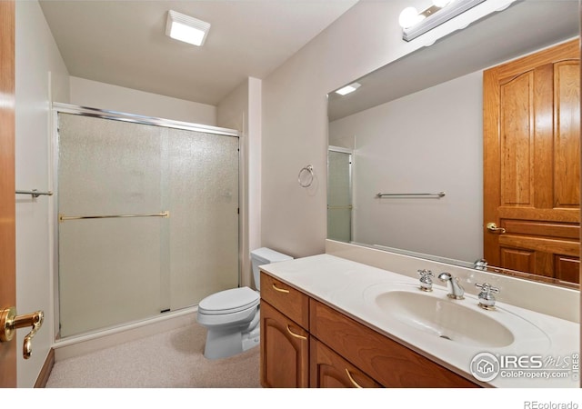 bathroom featuring vanity, toilet, and a shower with shower door