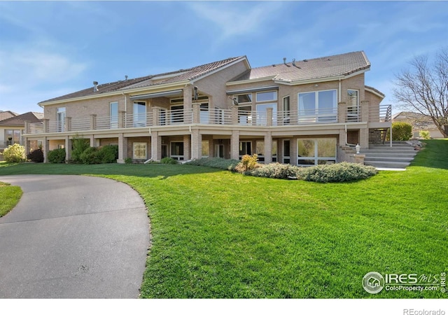 835 Rossum Dr, Loveland, CO 80537 - rear view of property featuring a yard, brick siding, and a balcony
