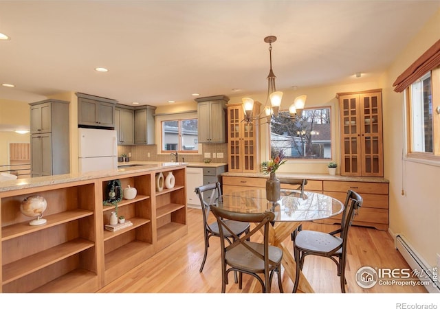 dining area with baseboard heating, a healthy amount of sunlight, a notable chandelier, and light wood-type flooring