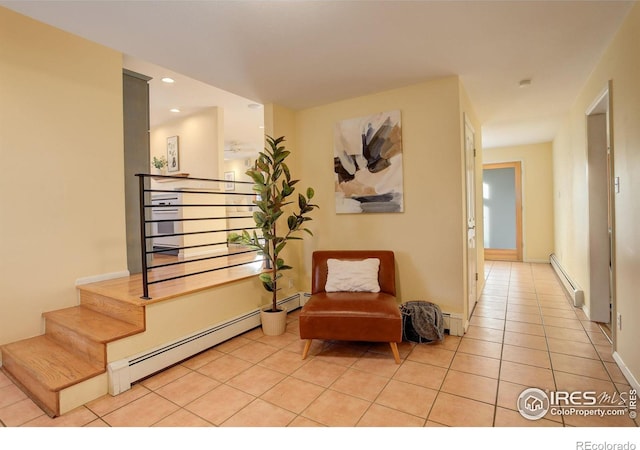 living area with a baseboard heating unit and light tile patterned flooring