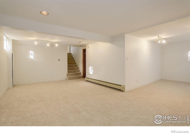 basement with baseboard heating, light carpet, and track lighting