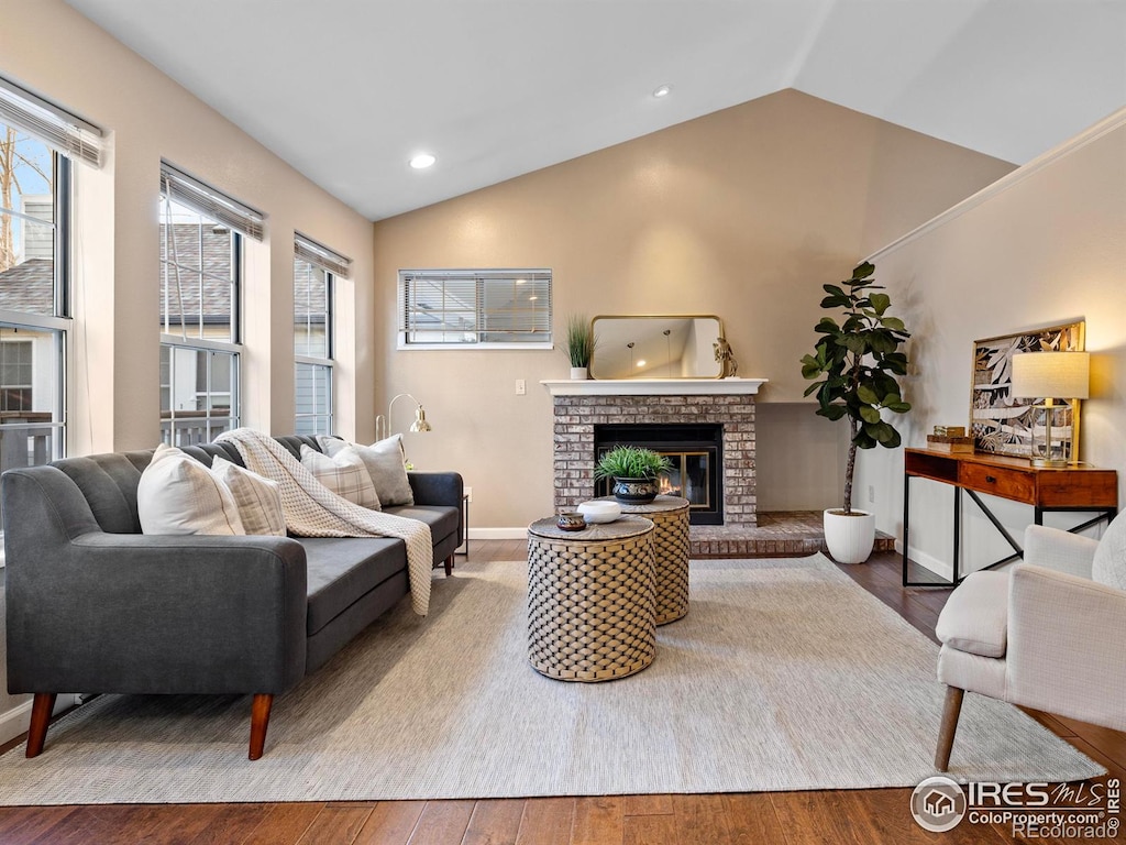 living room featuring a fireplace, wood-type flooring, and vaulted ceiling