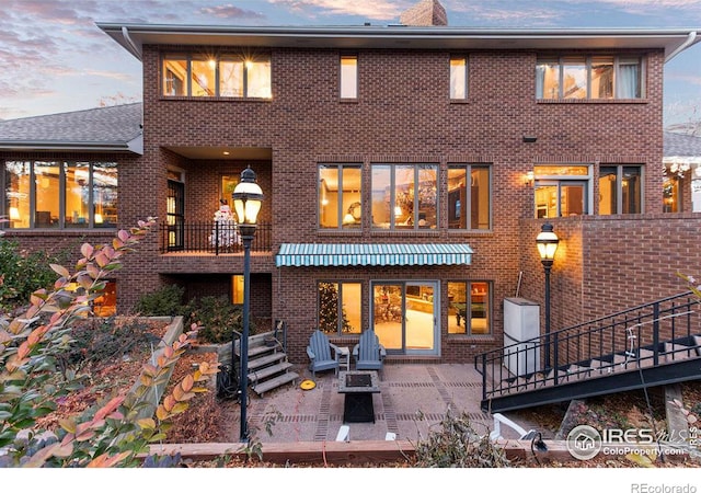 back house at dusk featuring a patio