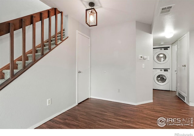 clothes washing area featuring stacked washer and dryer and dark wood-type flooring