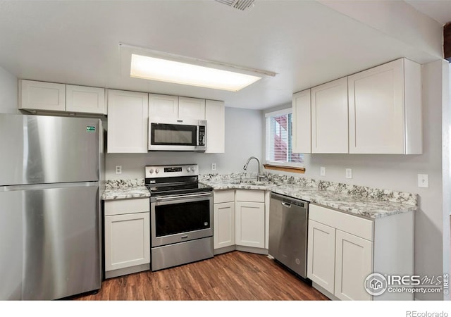 kitchen featuring white cabinets, sink, dark hardwood / wood-style floors, light stone counters, and stainless steel appliances