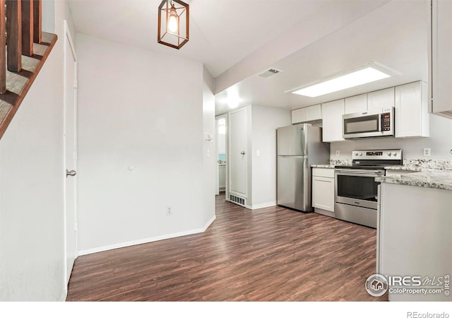 kitchen featuring light stone countertops, dark hardwood / wood-style flooring, white cabinetry, and stainless steel appliances