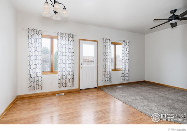 entrance foyer with ceiling fan with notable chandelier and hardwood / wood-style flooring