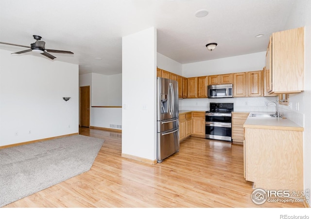 kitchen with light brown cabinets, sink, light wood-type flooring, and stainless steel appliances