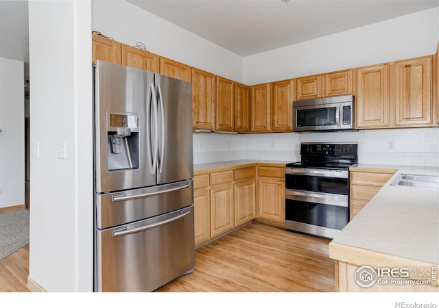 kitchen with sink, appliances with stainless steel finishes, and light hardwood / wood-style flooring