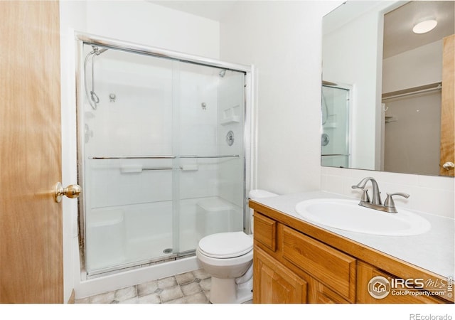 bathroom featuring a shower with door, vanity, and toilet