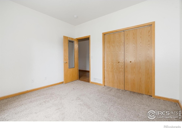 unfurnished bedroom featuring light carpet and a closet