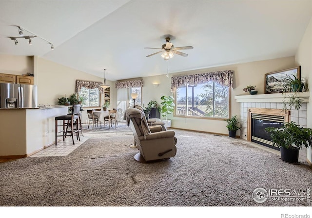 carpeted living room featuring a fireplace, track lighting, ceiling fan, and vaulted ceiling