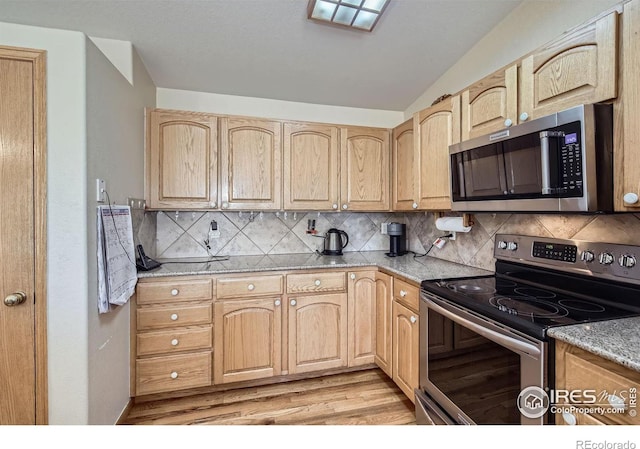 kitchen featuring light brown cabinetry, light stone counters, and stainless steel appliances