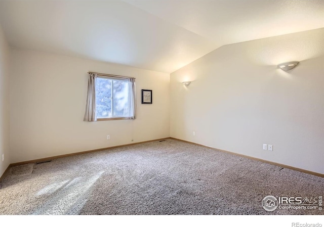 carpeted empty room with lofted ceiling