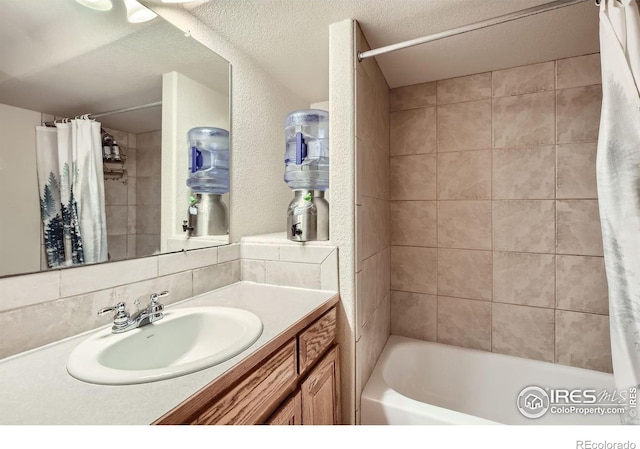 bathroom featuring vanity, decorative backsplash, shower / bath combination with curtain, and a textured ceiling