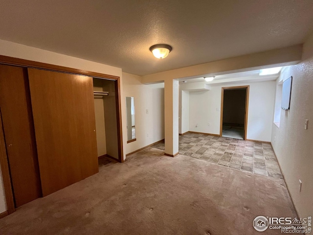 unfurnished bedroom with light colored carpet, a closet, and a textured ceiling