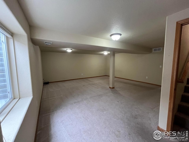 basement with light colored carpet and a textured ceiling