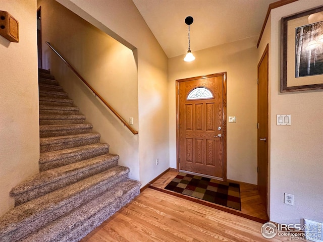 foyer entrance with hardwood / wood-style flooring and vaulted ceiling