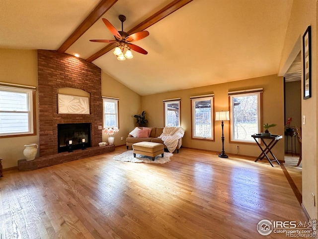 unfurnished living room with plenty of natural light, lofted ceiling with beams, a fireplace, and light hardwood / wood-style flooring